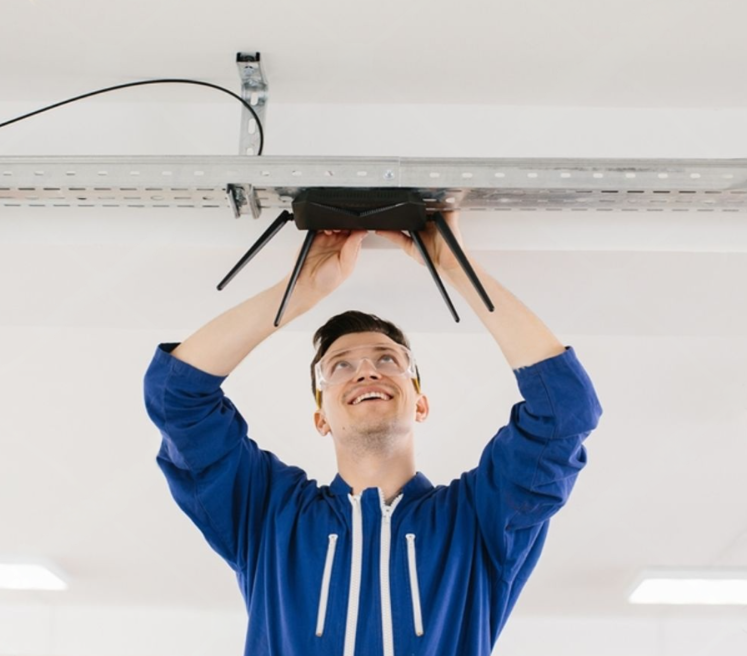 technician installing a new wireless router on the ceiling 
